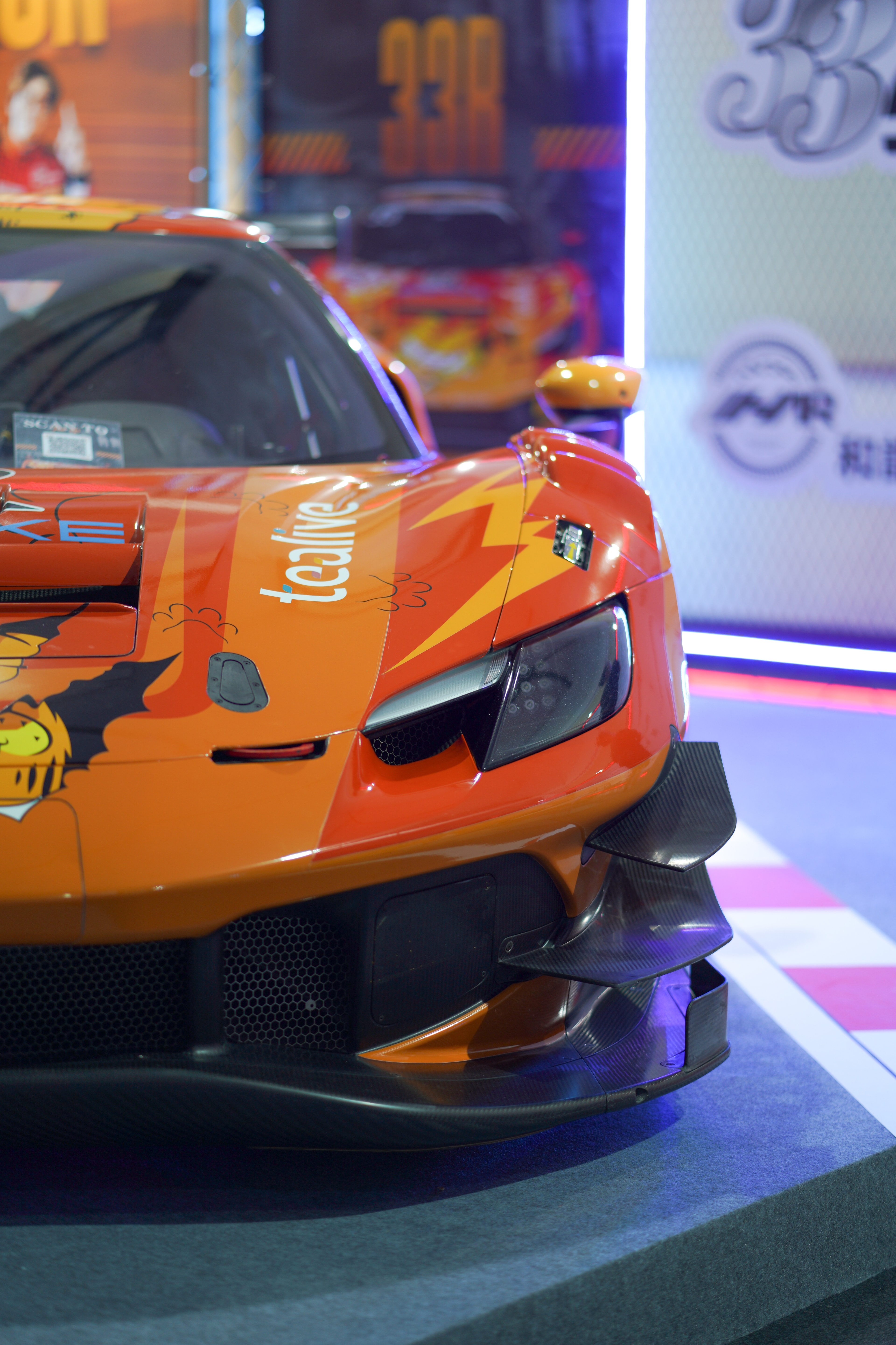 Front of an orange sports car at an automotive event